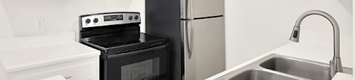 A black oven and fridge in a white kitchen at Bonnie Brae Apartments, California
