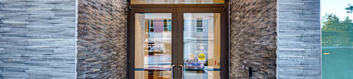 A modern building entrance with a glass door and a brick wall.