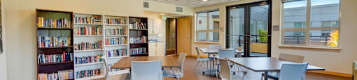 A room with a bookshelf and tables.