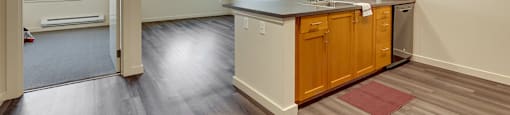 A kitchen with wooden cabinets and a red rug on the floor.
