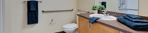 A bathroom with a toilet, sink, and mirror.