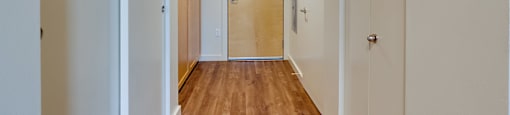 A long hallway with a wooden floor and white walls.