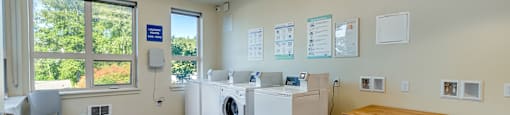 A laundry room with a washer and dryer, a chair, and a table.