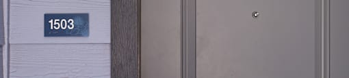 A grey door with a silver handle and a number plate on the wall.