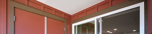 A room with a red door and a glass door leading to another room.