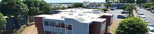 A building with a red and white exterior is surrounded by a parking lot and greenery.