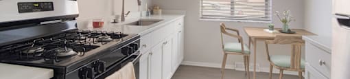 a kitchen with a stove top oven next to a table with a chair at Bedford Castle, Bedford Heights, OH 44146