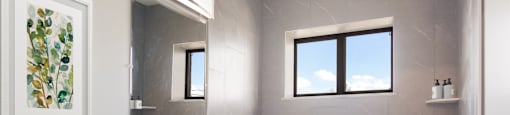 a bathroom with grey tiles and a white sink and bathtub at Bedford Castle, Bedford Heights, 44146