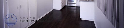 a kitchen with white cabinets and a dark wood floor