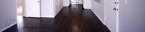 a view of a hallway with white walls and a dark wood floor