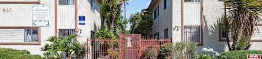 a sidewalk in front of two apartment buildings with a gate