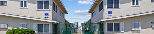 an apartment building with a yard and a green gate