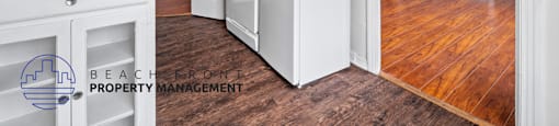 a kitchen with white cabinets and a refrigerator and a wood floor