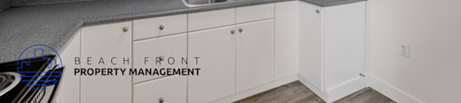 A kitchen with white cabinets and a grey countertop.