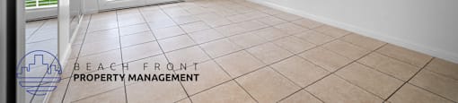 the living room of a house with a tiled floor and white walls