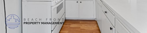 A kitchen with white cabinets and a stove top oven.