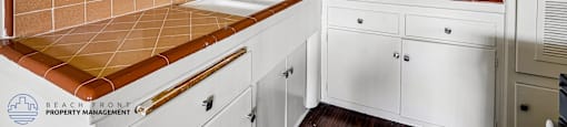 A kitchen with white cabinets and a brown tile backsplash.