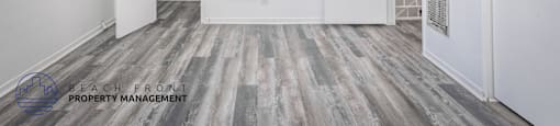 A spacious room with wooden flooring and white walls.