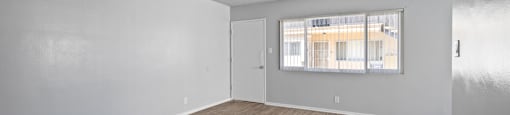 the living room of an apartment with wood flooring and a window