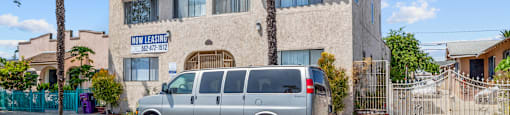 a silver van parked in front of a building with palm trees