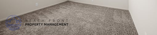 A room with a carpeted floor and a window with blinds.