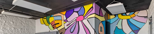 A colorful mural on the wall of a room with wooden flooring and a logo for Beach Front Property Management.