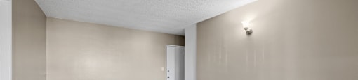 A room with a light on the wall and a door in the distance.
