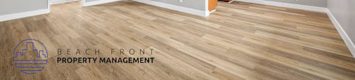 A spacious room with wooden flooring and a ceiling fan, managed by Beach Front Property Management.