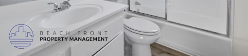 A white bathroom with a sink, toilet, and shower.