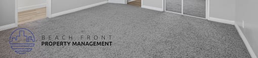 A spacious room with a ceiling fan and a logo for Beach Front Property Management.
