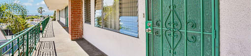 A green gate is on the right side of a white wall.