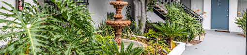 A courtyard with a fountain surrounded by plants and trees.