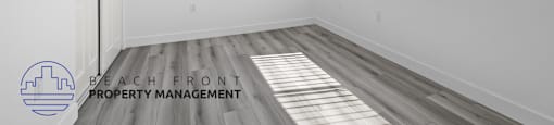 an empty room with wood flooring and a window