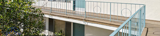 A white building with a blue door and a balcony.