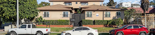 A white car is parked in front of a house with a sign that says Beachfront Property Management.