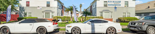 Three white cars are parked in front of a building with a sign that reads "Beach Front Property Management.".