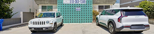 A white car is parked in front of a FOR RENT sign.