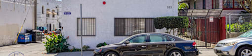 A black car is parked in front of a white house with a sign that reads 525.