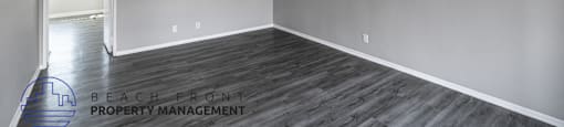 A room with wooden flooring and a logo for Beach Front Property Management.