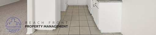 A kitchen with white cabinets and a tile floor.