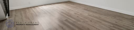 A room with wooden flooring and a window with blinds.