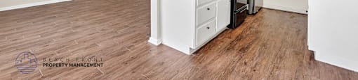 A kitchen with white cabinets and a wooden floor.