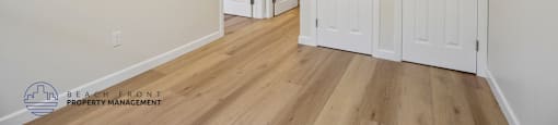 A room with white doors and wooden floors.