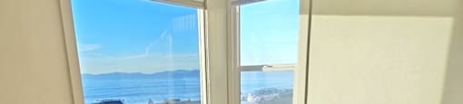 A room with a ceiling fan and a window overlooking the beach.