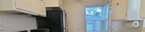 A kitchen with black appliances and white cabinets.