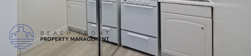 a white kitchen with white appliances and a mirror and a stove top oven and sink