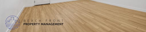 a living room with white walls and wooden floors and a white door