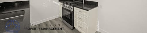 A kitchen with white cabinets and black countertops.