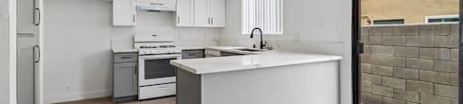 A modern kitchen with white cabinets and a wooden floor.