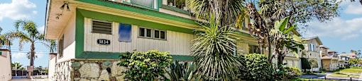 A green and white house with a stone wall in front.